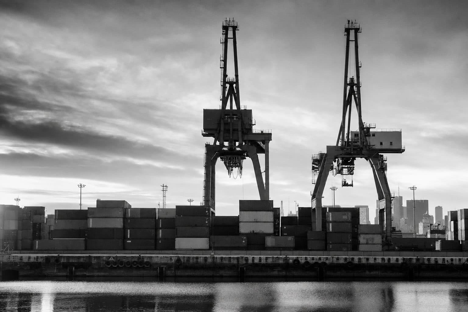 Puerto de Buenos Aires al amanecer — grúas pórtico y contenedores apilados, fotografía documental en blanco y negro.